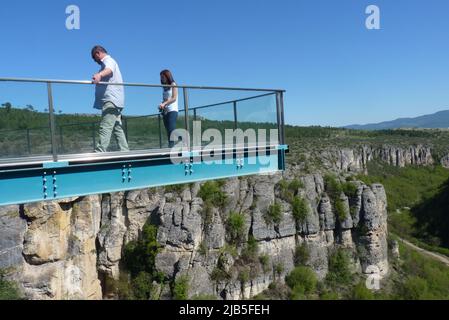 Deux personnes sur la passerelle en métal surélevée surplombant la falaise accidentée et la végétation Banque D'Images