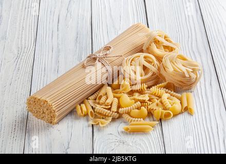Différents types et formes de pâtes italiennes sur fond de bois blanc Banque D'Images