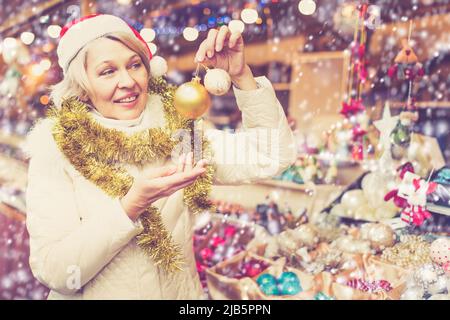 Portrait d'une femme mûre heureuse en chapeau avec des jouets de Noël Banque D'Images