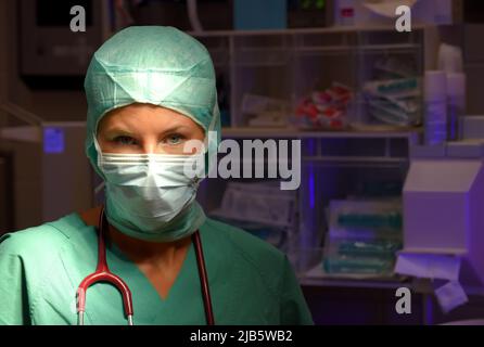 Une infirmière de théâtre d'anesthésie est vue dans un théâtre d'opération. Elle est vue vêtue de vêtements médicaux verts stériles avec un masque facial sur son visage. Banque D'Images