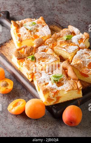 Génoise aux abricots, saupoudrée de sucre glace sur le panneau en bois de la table. Verticale Banque D'Images