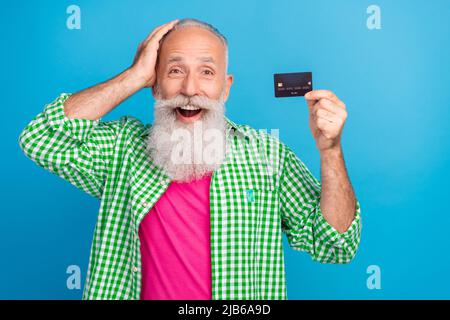 Photo d'une personne excitée et stupéfait toucher la main tête ouverte bouche ouverte démontrer carte de débit isolée sur fond bleu Banque D'Images