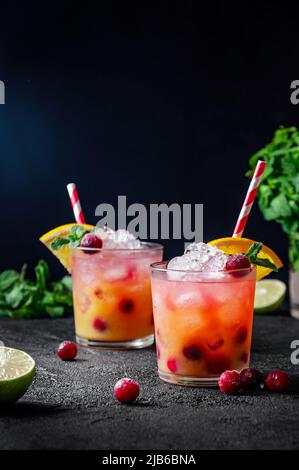 Cocktail avec rhum ou vodka, soda, canneberge, jus d'orange, citron vert et menthe dans le verre sur fond gris foncé Banque D'Images