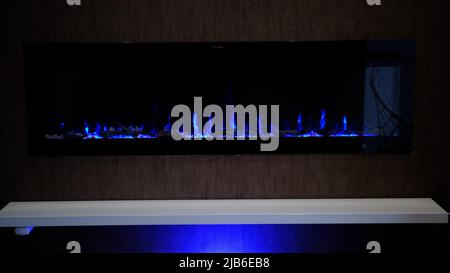 vue sur cheminée électrique avec flamme artificielle étincelante, décor pour l'intérieur, flamme bleue sur cristaux avec rétroéclairage bleu. Banque D'Images