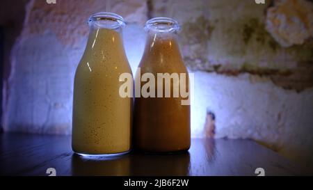 Milk-Shake au chocolat et à la crème glacée, et Milk-Shake à la vanille servis dans une bouteille de verre d'époque. Avec arrière-plan bleu foncé et mouvement léger. Banque D'Images