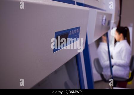 Une chercheuse travaille dans une cabine avec filtre hepa à l'intérieur d'un laboratoire de culture de tissus cellulaires Banque D'Images