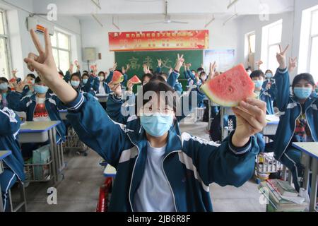 HANDAN, CHINE - 3 JUIN 2022 - trois étudiants seniors montrent les pastèques qu'ils reçoivent et montrent leurs gestes gagnants pour se réjouir, 3 juin, Banque D'Images