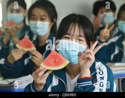 HANDAN, CHINE - 3 JUIN 2022 - trois étudiants seniors montrent les pastèques qu'ils reçoivent et montrent leurs gestes gagnants pour se réjouir, 3 juin, Banque D'Images