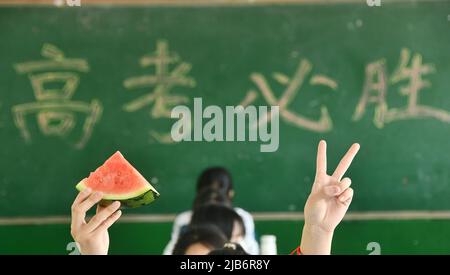 HANDAN, CHINE - 3 JUIN 2022 - trois étudiants seniors montrent les pastèques qu'ils reçoivent et montrent leurs gestes gagnants pour se réjouir, 3 juin, Banque D'Images