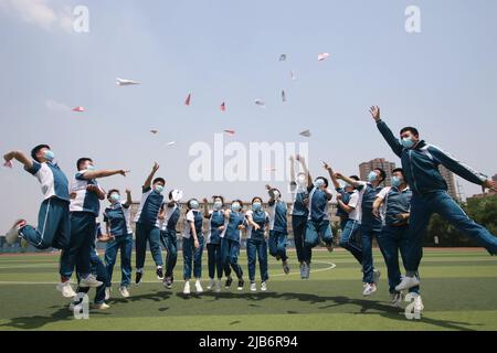 HANDAN, CHINE - 3 JUIN 2022 - trois étudiants seniors lancent des avions en papier avec leurs rêves dans les airs à Handan, province de Hebei, 3 juin 2022. Banque D'Images