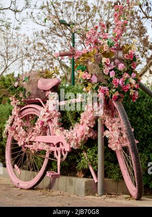 un vélo rose décoré de fleurs est laissé dans la rue en gros plan. Banque D'Images