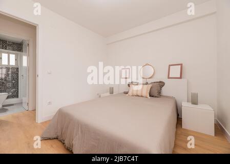 Chambre avec lit double avec miroir rond, couvre-lit gris, accès aux toilettes et au dressing Banque D'Images