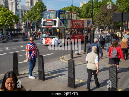 Un homme dans un T-shirt drapeau de l'Union s'arrête alors que les gens passent devant la place du Parlement à Londres. Le tourisme est une industrie énorme à Londres. Banque D'Images