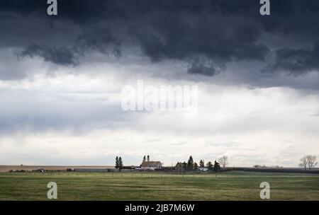 Une tempête de grêle se forme au-dessus d'une ferme dans les Prairies canadiennes lors d'un événement météorologique extrême dans le comté de Rocky View Alberta Canada. Banque D'Images