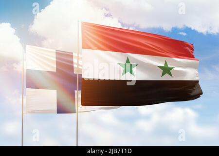 Ciel bleu ensoleillé et drapeaux de la syrie et de la finlande Banque D'Images