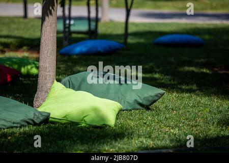 Étudiants assis sur des coussins sous les arbres Banque D'Images