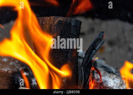 Flammes orange vives et massives provenant d'une bûche mesquite dans une fosse de feu. Banque D'Images