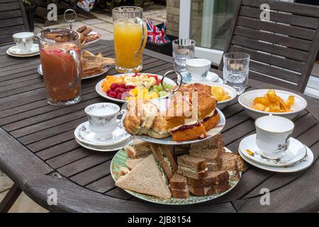 Le jour férié du Jubilé platine de la Reine - table pour un thé d'après-midi en famille dans le jardin avec sandwiches, gâteaux, thé, jus de fruits et fruits, juin 2022 Banque D'Images
