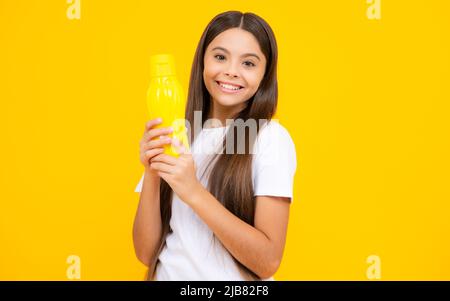 L'adolescent tient une bouteille d'eau isoaltée sur le jaune. Hydratation du corps de la garde d'enfants. Loisirs actifs et équilibre de l'eau. Un enfant en bonne santé et actif boit de l'eau Banque D'Images