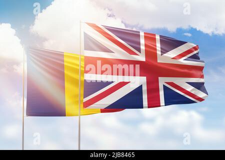 Ciel bleu ensoleillé et drapeaux du royaume-uni et de la roumanie Banque D'Images