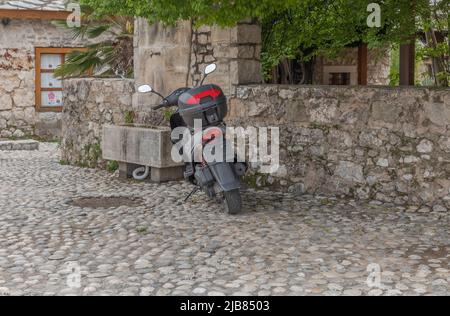 Mobylette avec une arrière-boîte et des miroirs d'aile garés près d'un mur dans les rues arrière de l'ancien village de Pocitelj un site classé au patrimoine mondial de l'UNESCO Banque D'Images