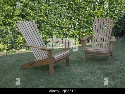 Des chaises longues en bois à l'ancienne se sont assises sur une pelouse contre une haie de Laurier Banque D'Images