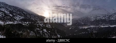 Vues de l'après-midi enneigées et moody depuis la vue aérienne du sommet de la montagne au début de l'hiver dans le nord du Canada. Banque D'Images