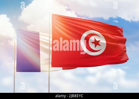 Ciel bleu ensoleillé et drapeaux de la tunisie et de la france Banque D'Images