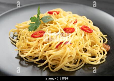 Spaghetti traditionnels italiens aglio sur une assiette noire. Gros plan Banque D'Images