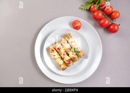 Cannelloni italien avec fromage à la viande et sauce tomate sur fond gris dans une assiette grise. Vue de dessus Banque D'Images