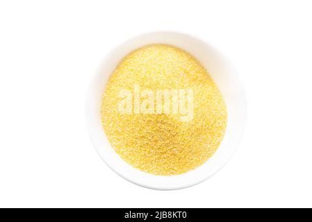 Tas de polenta ou de farine de maïs dans un bol blanc. Maïs séché moulu ou grains de maïs. Vue de dessus, espace de copie. Concept de grains sains. Isolé Banque D'Images