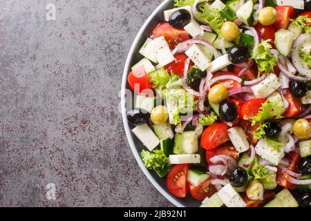 Salade grecque aux légumes frais, fromage feta et olives noires dans une assiette sur la table. Vue horizontale du dessus Banque D'Images