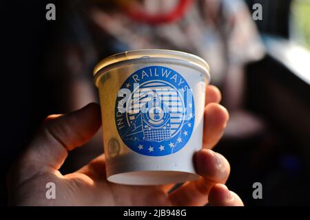 Inde - janvier 2017 : main de l'homme tenant une coupe en papier avec l'inscription Indian Railway et l'image d'un train bleu qui est le logo du chemin de fer indien Banque D'Images