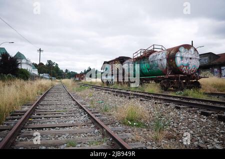 Osorno, Chili - février 2020 : wagon abandonné avec citerne couvert de graffiti sur les voies ferrées. Ancienne gare d'Osorno sur la gauche Banque D'Images