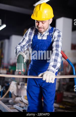 Homme de 20-30 ans utilise une scie sauteuse électrique pour les travaux de construction Banque D'Images