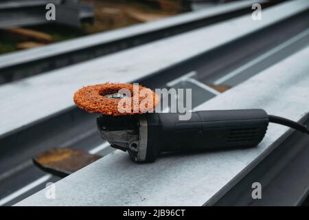 Ponceuse pour poutres métalliques sur chantier. Petite machine à meuler moderne et portable professionnelle sur colonne d'aluminium, personne. Pale d'éolienne Banque D'Images