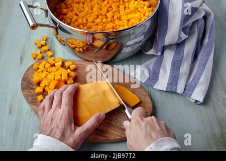 Le processus de trancher la citrouille sur une planche à découper et dans une casserole. Mains femelles avec un couteau. Cuisine maison Banque D'Images