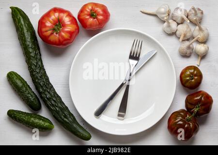 Un cadre de légumes maison sur une table en bois avec une plaque blanche pour la mise en place des aliments. Journée mondiale végétarienne Banque D'Images