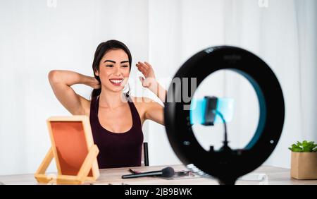 Jeune femme qui vante en ligne avec smartphone CAM et anneau conduit de la maison - les gens du millénaire avec les médias sociaux et le concept de travail intelligent Banque D'Images