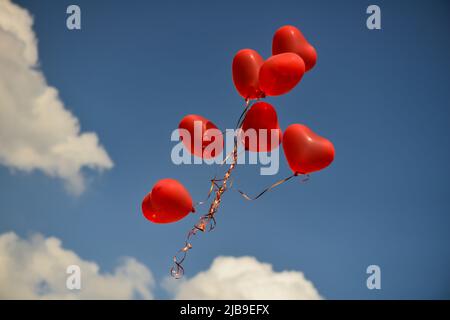 Ballons en forme de coeur rouge flottant dans le ciel. symbole de la Saint-Valentin Banque D'Images