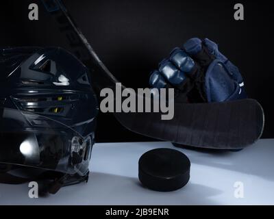 Helsinki / Finlande - 4 JUIN 2022 : gros plan de l'équipement de hockey sur glace sur fond sombre. Casque, bâton, palet et gants de hockey sur glace Banque D'Images