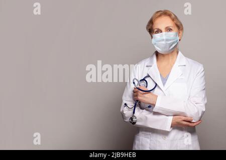 Médecin portant un masque médical debout sur fond gris Banque D'Images