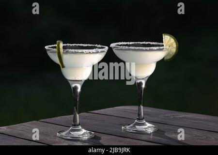 Deux verres avec cocktail de margarita frais sur une table en bois sur un patio soir d'été, foyer sélectif Banque D'Images