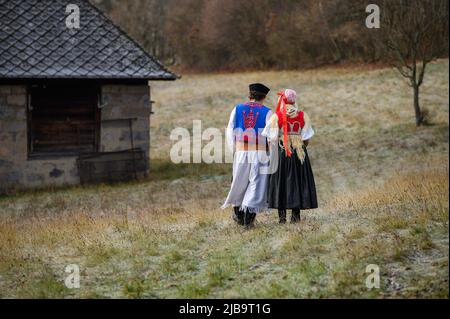 Un couple vêtu d'un costume folklorique traditionnel. Costume slovaque dans la nature d'automne. Ancienne maison de campagne en arrière-plan. Jeune couple en costume folklorique wal Banque D'Images