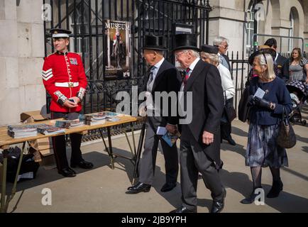 Deux hommes âgés en haut des chapeaux marchent avec leurs épouses devant une armée de Coldstream Guards sargeant à Londres. Banque D'Images