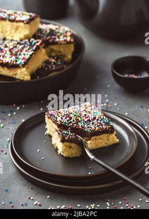 Délicieux gâteau fait maison avec glaçage au chocolat noir et saupoudrage de sucre coloré servi sur une assiette. Style rustique. Mise au point sélective. Banque D'Images