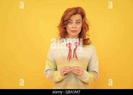 femme surprise redhead avec coeur rouge bâtons sur fond jaune. amour Banque D'Images