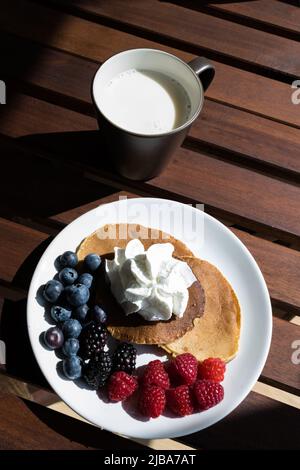 vue de dessus des crêpes avec crème, bleuets et raisins avec un verre de lait Banque D'Images