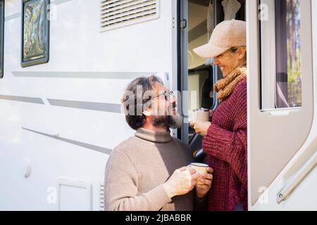 Couple d'âge mûr Profitez d'activités de loisirs à l'extérieur d'une camionnette de camping avec tasse à café. Les voyageurs sourient à l'extérieur. Vacances avec location de Motor home vehic Banque D'Images