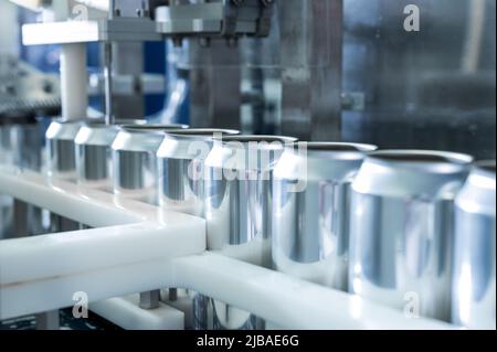 Vider les nouvelles canettes en aluminium pour le traitement des boissons dans la ligne d'usine sur la machine à tapis convoyeur lors de la fabrication des boissons. Concept commercial industriel de l'industrie agroalimentaire. Photo de haute qualité Banque D'Images